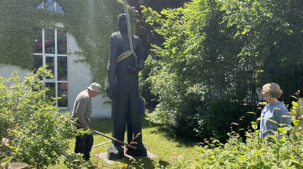 Josef Lang stellt seine Skulptur "Ahnenfigur" im Garten des studioRose auf